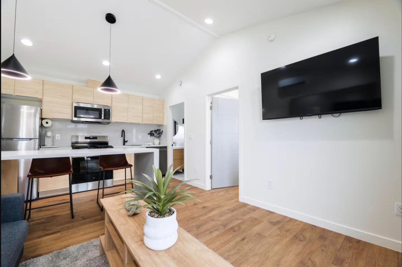 Kitchen and living area of the Covina ADU with island seating, pendant lights and wall-mounted TV