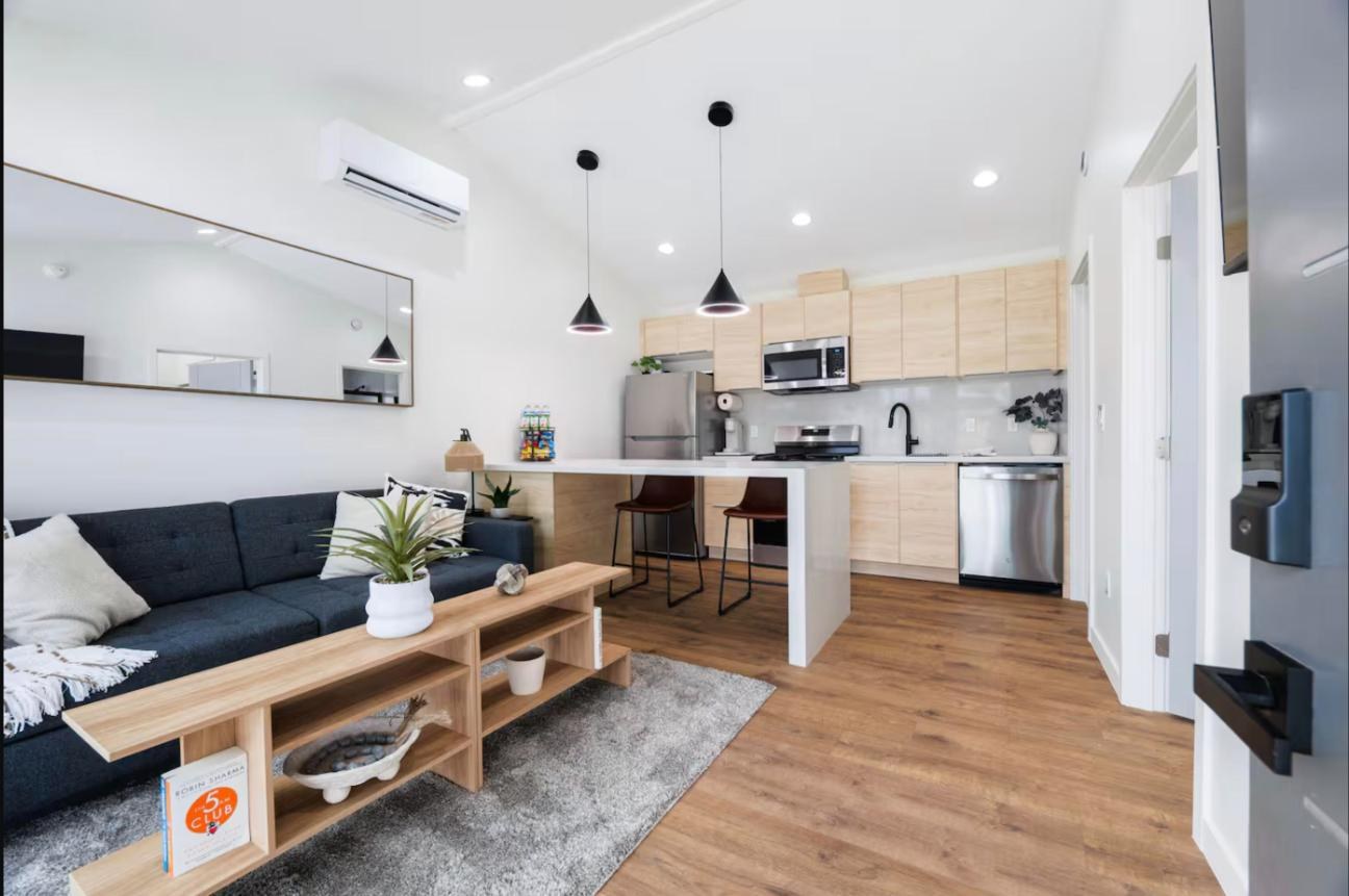 Open living room and kitchen with vaulted ceiling, navy sofa, oak coffee table and pendant lights