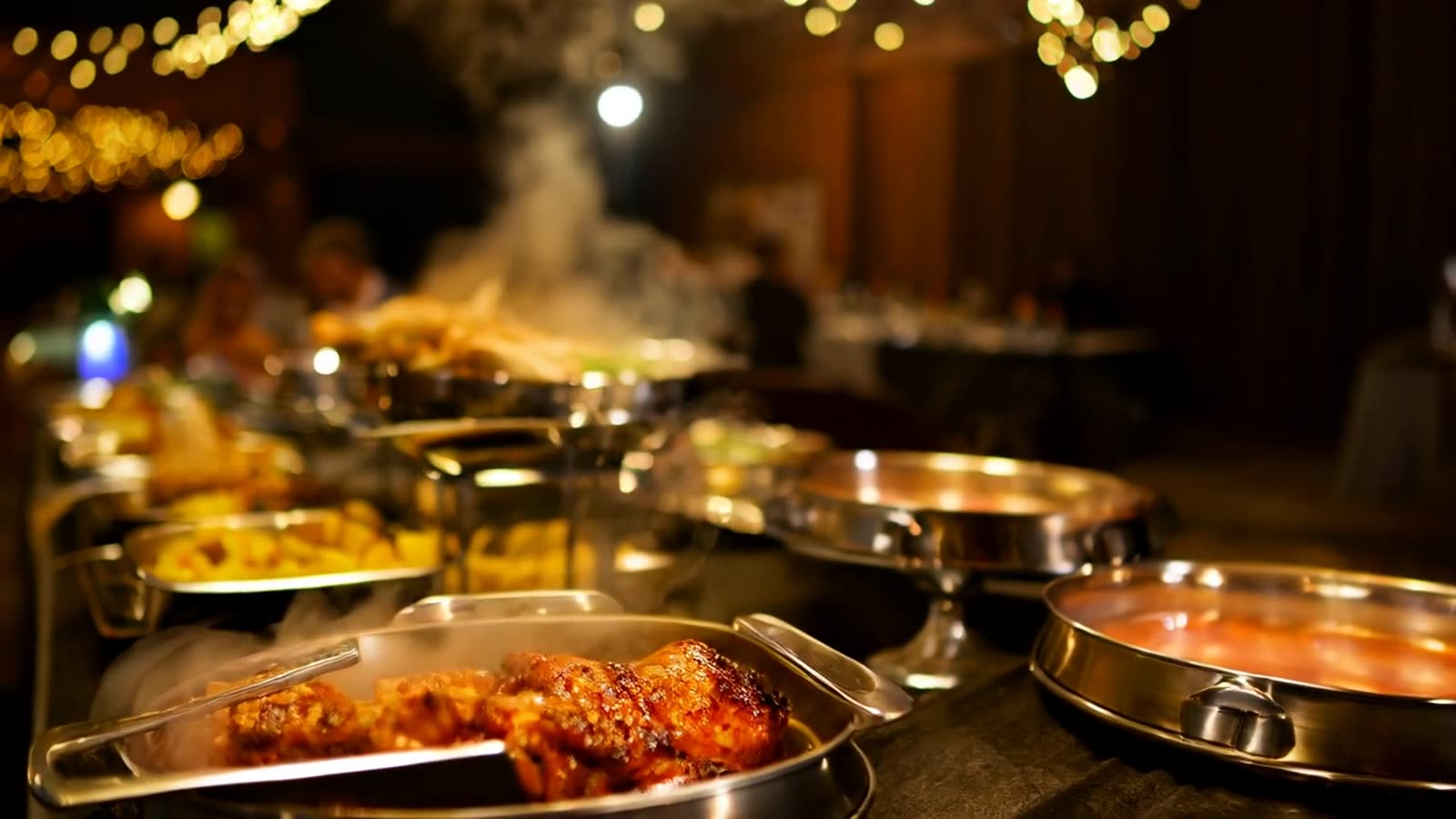Evening wedding buffet with steaming chafing dishes and string lights