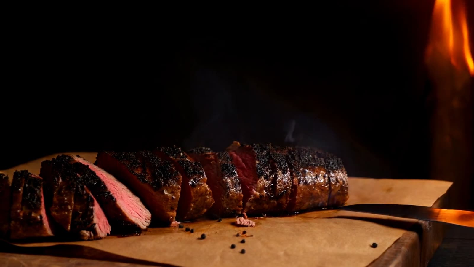 Smoked brisket sliced on butcher paper in firelight